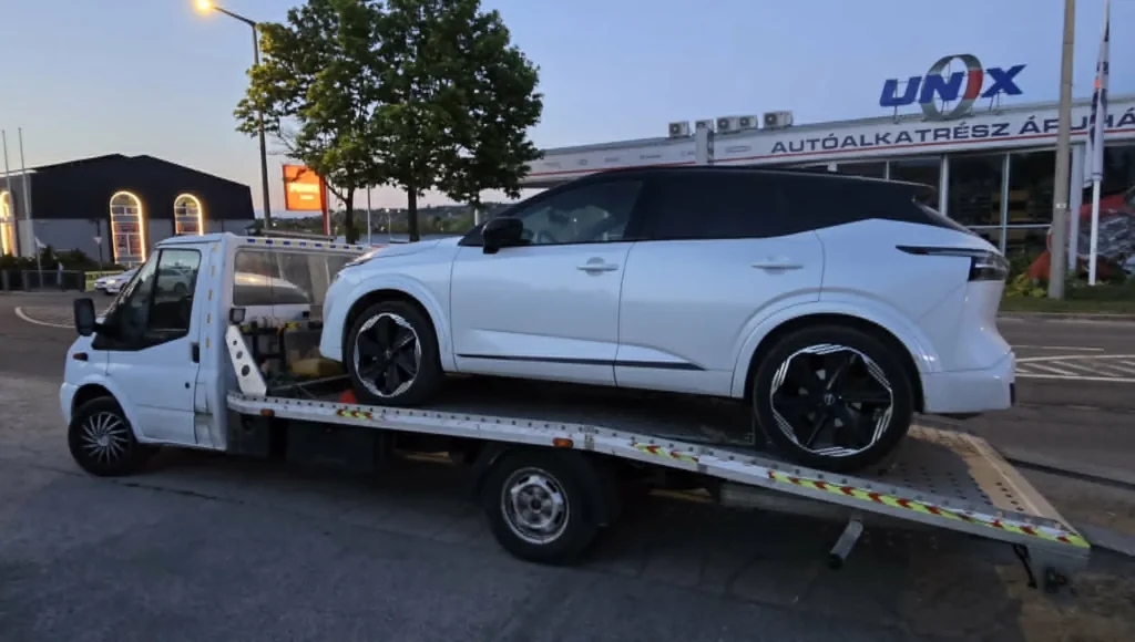 Fehér Nissan Qashqai a platós mentőautón, szállítás előtt
